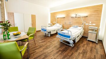 Zweibettzimmer mit Tisch und Sesseln der Privatklink Leech.